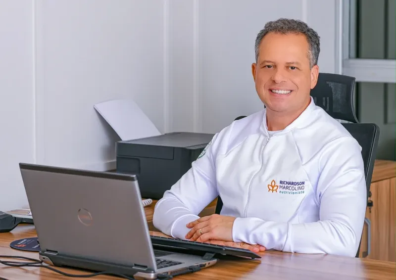 Richardson Marcolino, nutricionista, trabalhando em seu consultório com notebook